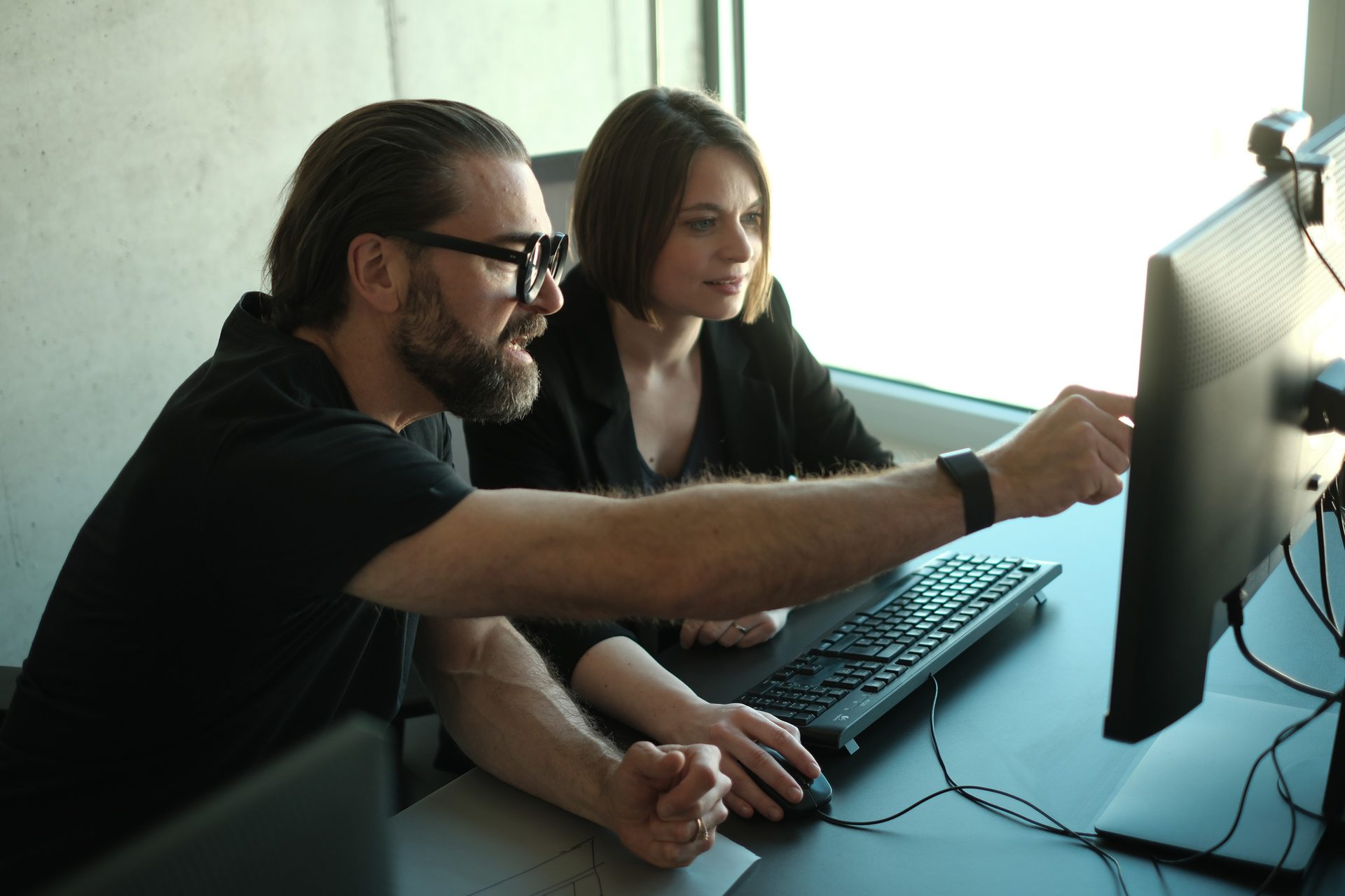 Two colleagues in front of the screen, one pointing at the model