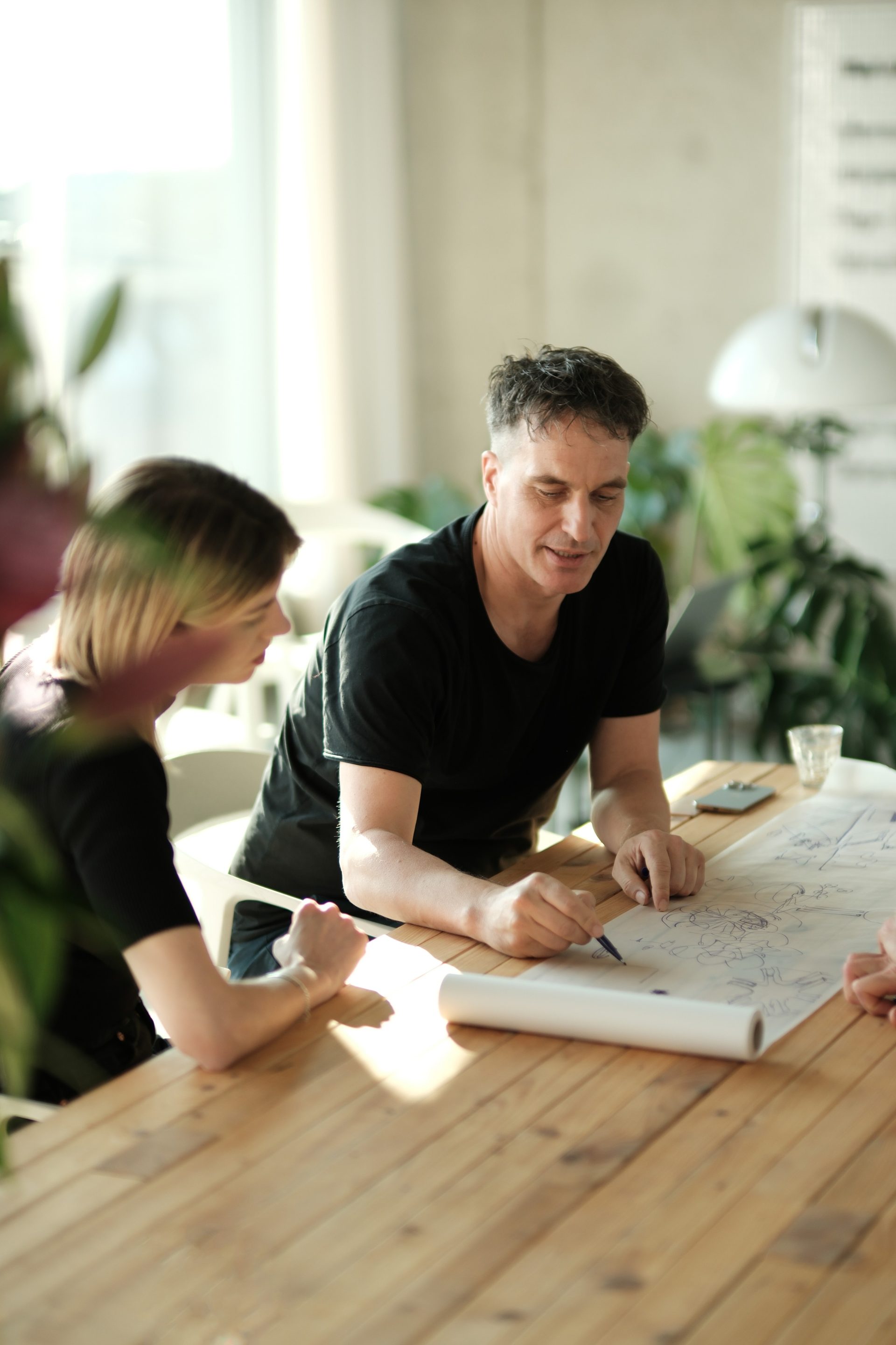 Two colleagues leaning over a drawing on the meeting table